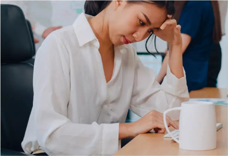 机で疲れている女性がジムに行けず悩んでいる様子